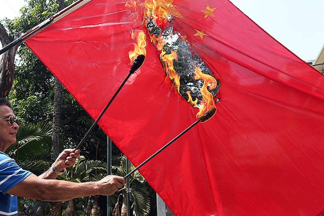 Retired Filipino police officer and former town mayor Abner Afuang burns a Chinese flag in protest over territorial disputes in the South China Sea. Photo: EPA