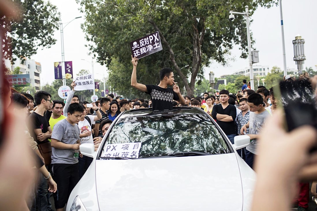 A man raises a placard which reads "Oppose PX (paraxylene petrochemicals), give me back my pure land", as he and other residents protest against a chemical plant project in Maoming, Guangdong province. Photo: Reuters