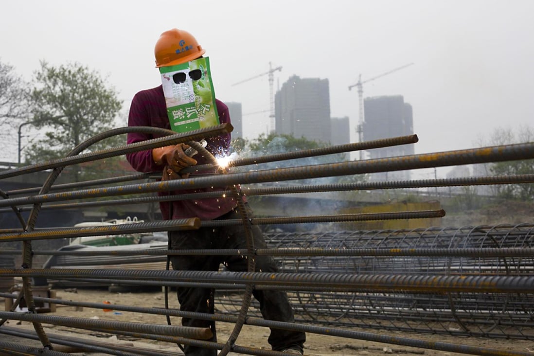 A welder improvises his mask at a site in Zhejiang province. Steel output growth is seen slowing to 3 per cent this year. Photo: Reuters