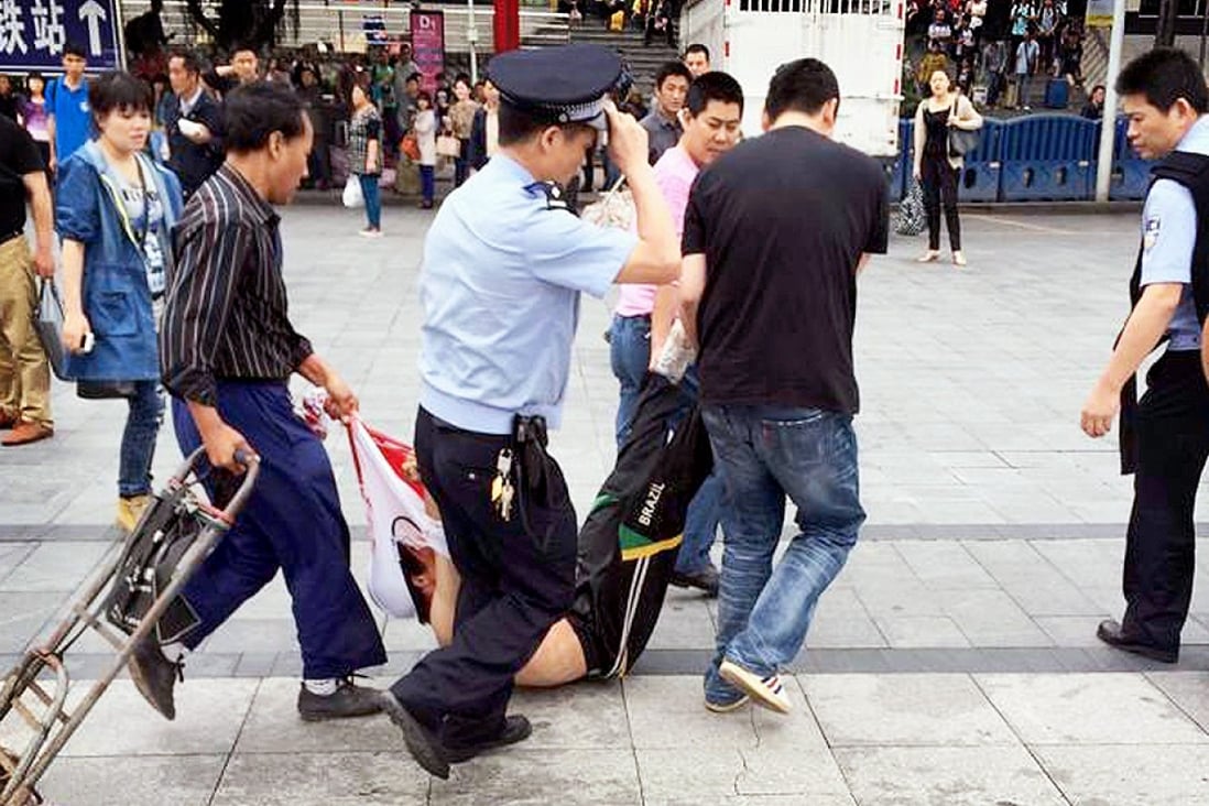 A man, whom local media say is a suspect, is detained after a knife attack at a railway station in Guangzhou. Photo: Reuters