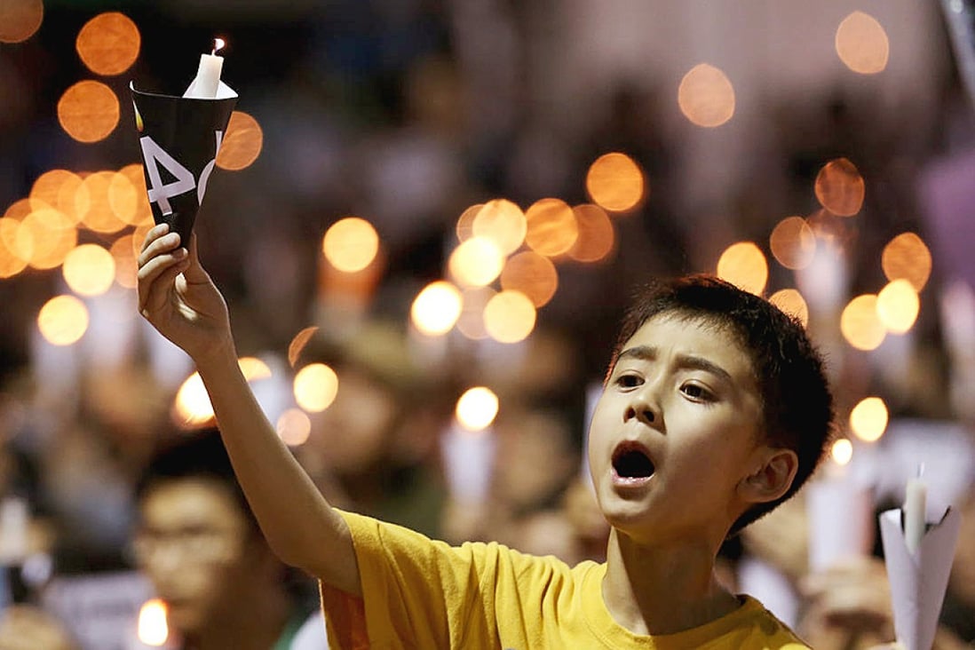 A youngster holds up a candle to commemorate those who died in the Tiananmen Square crackdown at the massive rally in Victoria Park last night, which organisers said drew a record crowd. Photo: Nora Tam