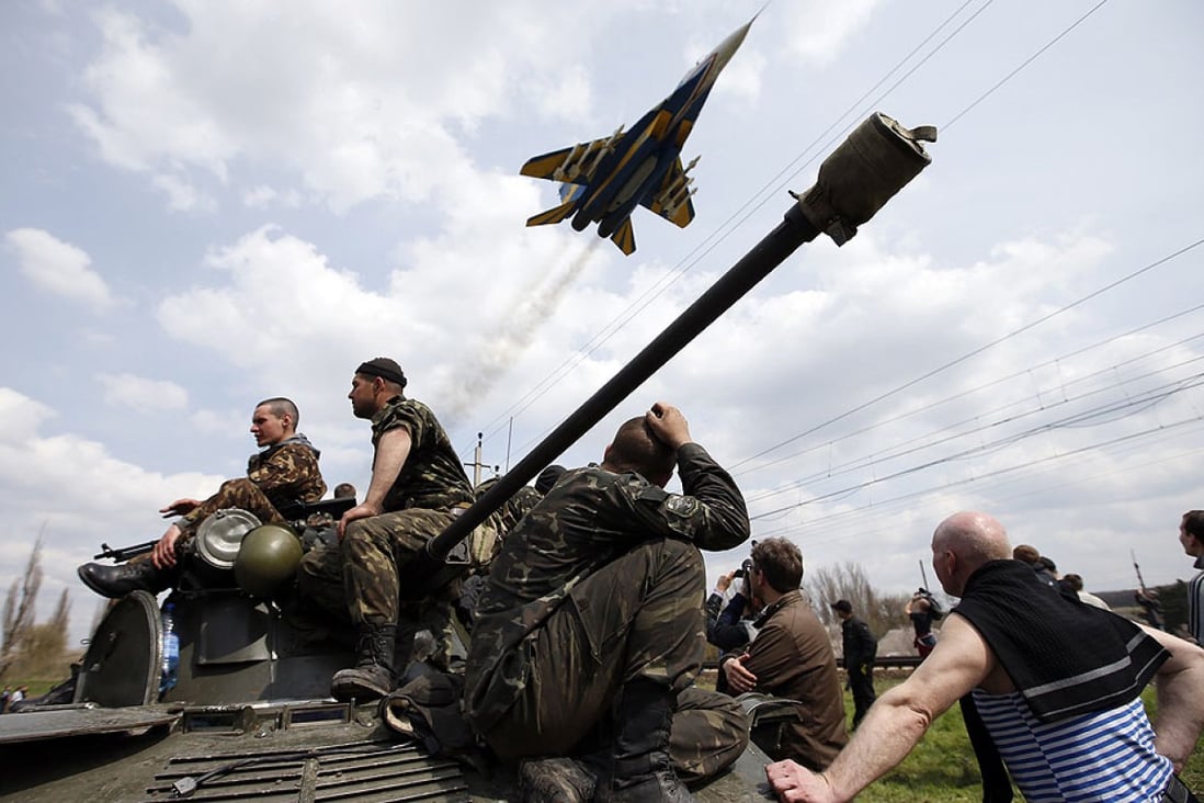 A fighter jet flies above as Ukrainian soldiers sit on an armoured personnel carrier. Photo: Reuters