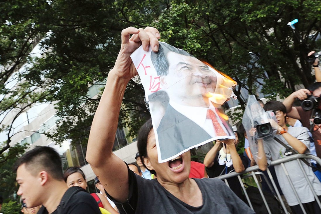 A League of Social Democrat activist calls for Chief Executive Leung Chun-ying to step down as she burns a portrait of him. Photo: David Wong