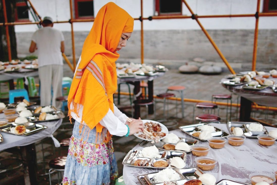 A woman distributes food on a table as she waits to break fast with other devotees on the first day of Ramadan at the Niujie Mosque in Beijing. Photo: Reuters