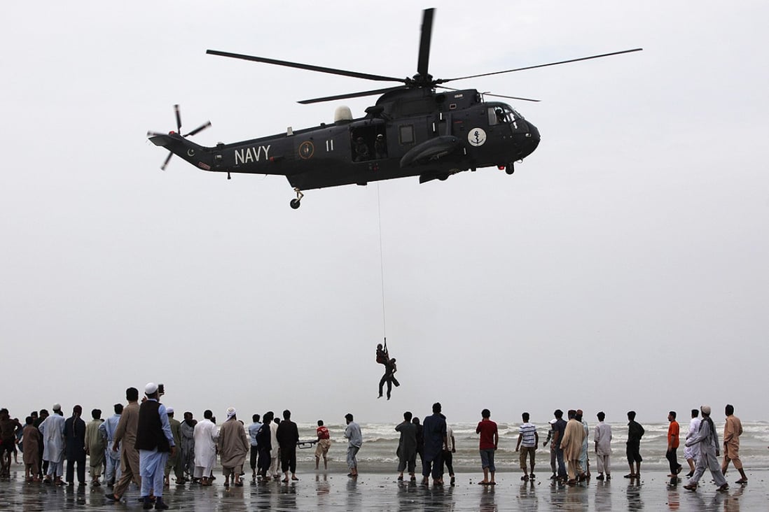 A Pakistan Navy diver hanging from a helicopter holds the body of a drowned man after recovering it from Arabian Sea off Karachi's Clifton beach. Photo: Reuters