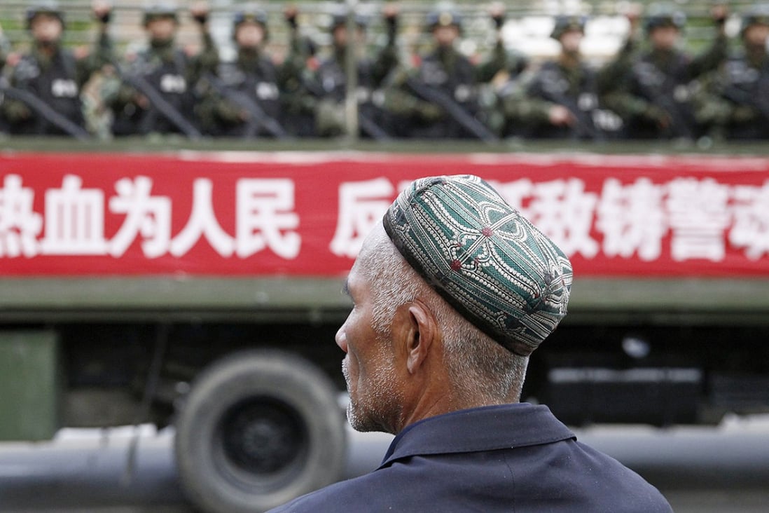 A Uyghur man looks on as a truck carrying paramilitary policemen travel along a street during an anti-terrorism oath-taking rally in Urumqi. Photo: Reuters