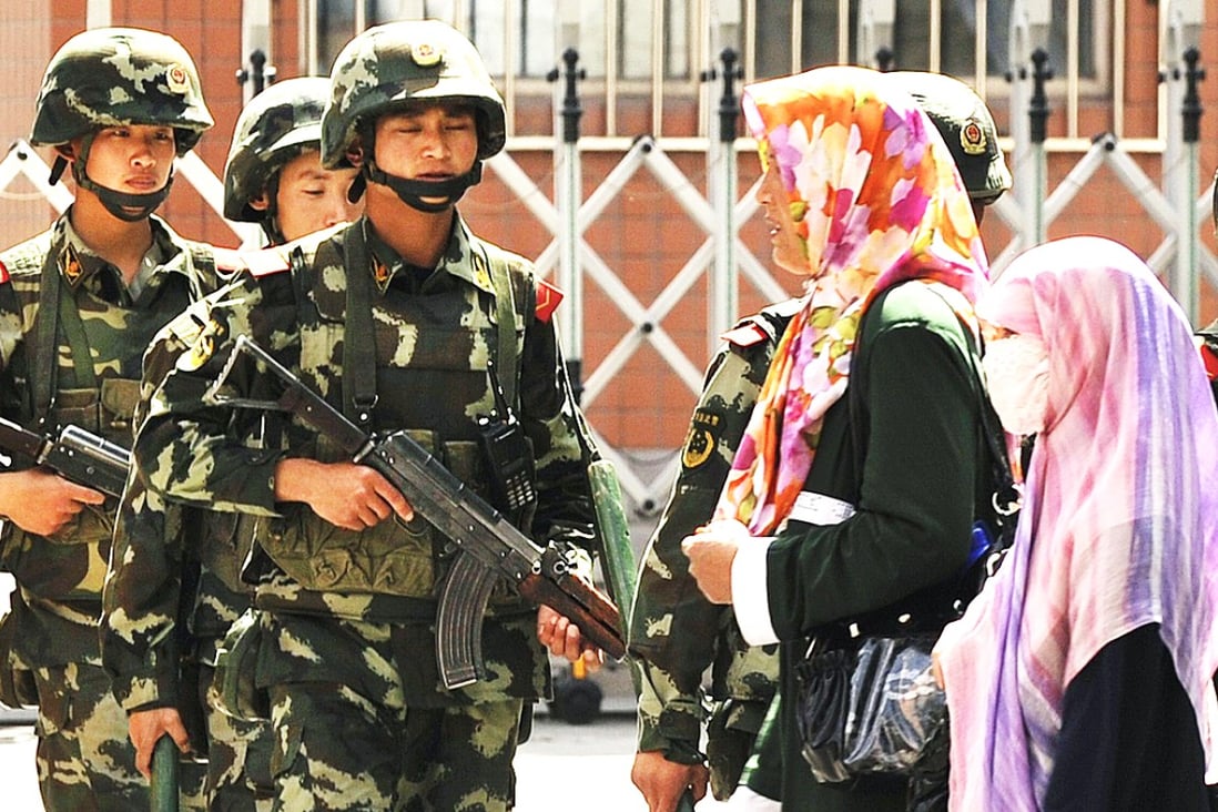 Uygur women pass a Chinese paramilatary police on patrol in Urumqi, the capital of Xinjiang. Burqas, niqabs and other Muslim wear are now banned on public buses in Karamay city. Photo: AFP