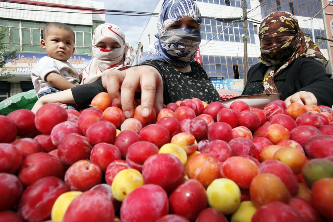 Uygur women buy fruit at a street stall in Urumqi, the capital of Xinjiang. A small county of more than 100,000 people is offering cash incentives and benefits to those who register their inter-ethnic marriages to promote 'stability'. Photo: AP
