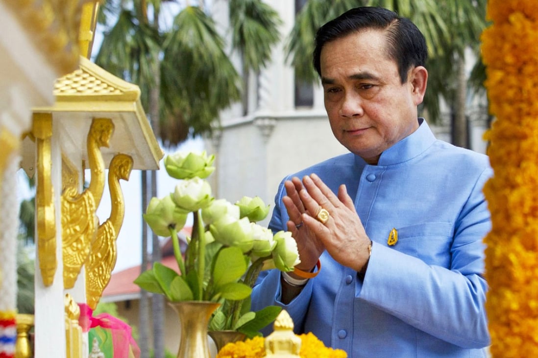 Thailand's Prime Minister General Prayuth Chan-ocha prays in front of the spirit house for good luck. Photo: AP