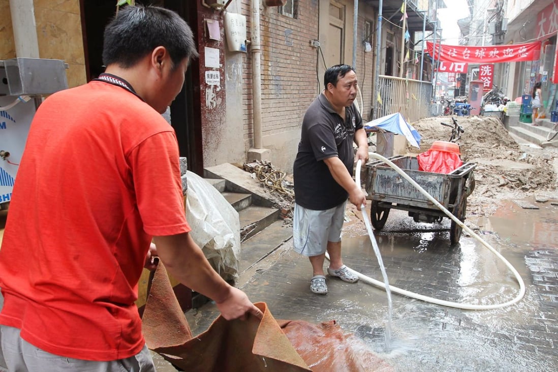 Residents wash a rug with water from illegal well. Photo: SCMP