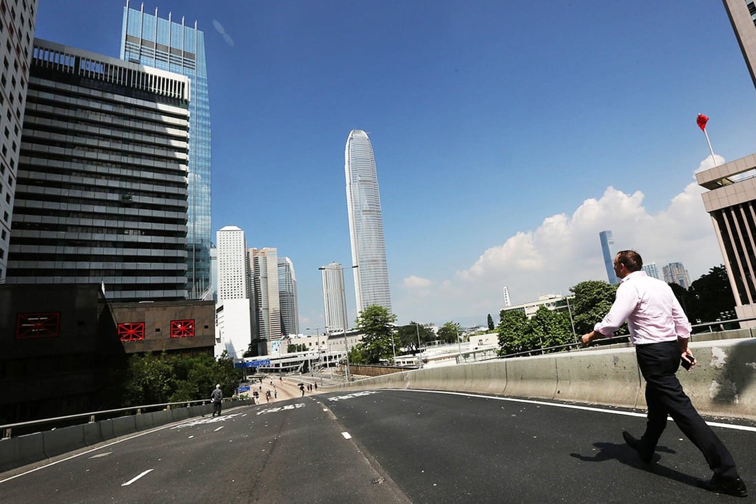 Pedestrians enjoy fresher air and a clear blue sky as they make their way along empty Connaught Road in Central yesterday. Photo: Felix Wong