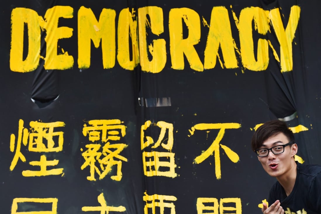 A pro-democracy protester stands next to a banner in Hong Kong. Photo: AFP