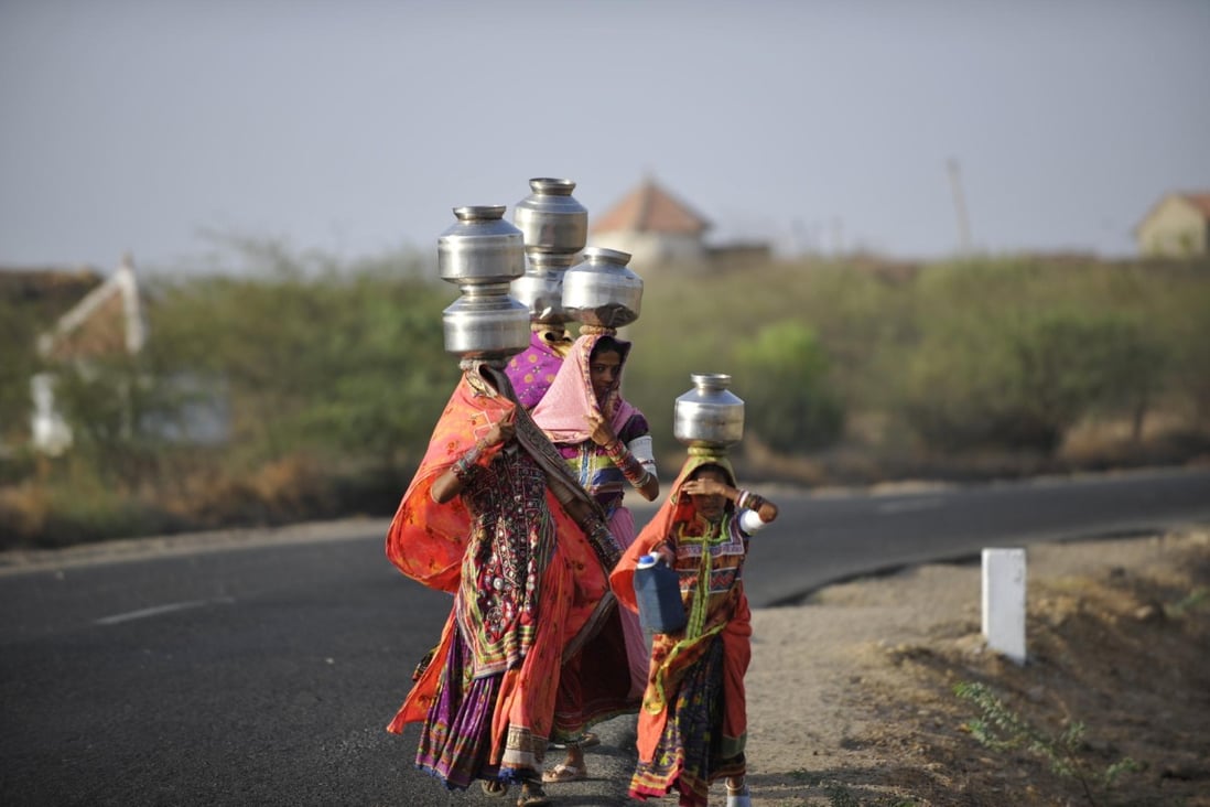 Tribal women balance steel pots of water on their heads in Banni, in Gujarat state, India.