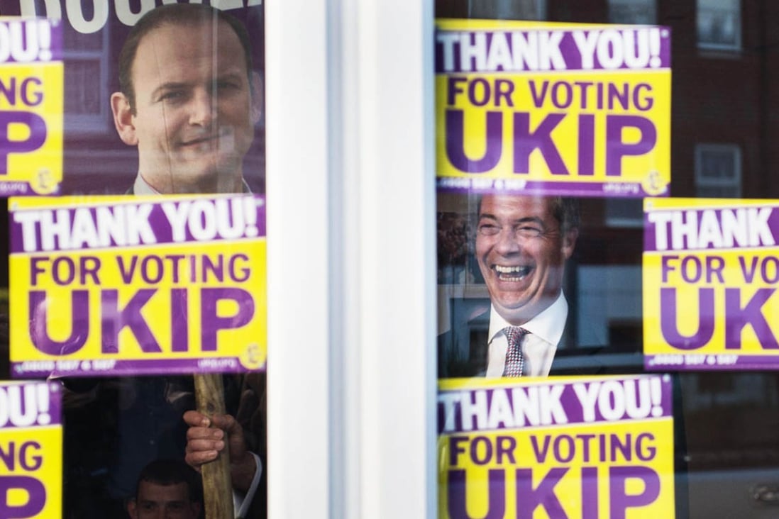 Ukip leader Nigel Farage in triumphant laughter as he glances out from behind the window of his party's campaign headquarters in Clacton yesterday. Photo: AP
