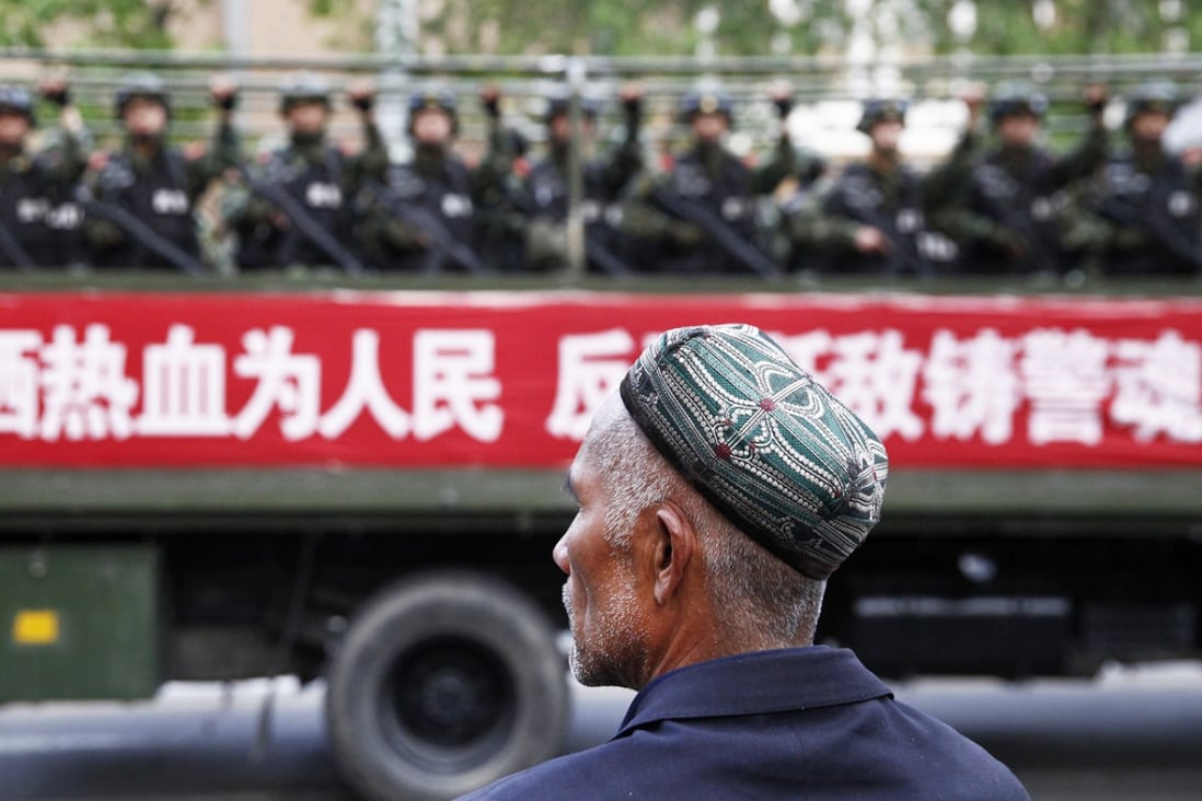 A Uygur man looks on as a truck carrying paramilitary policemen travels along a street during an anti-terrorism oath-taking rally in Urumqi. Photo: Reuters