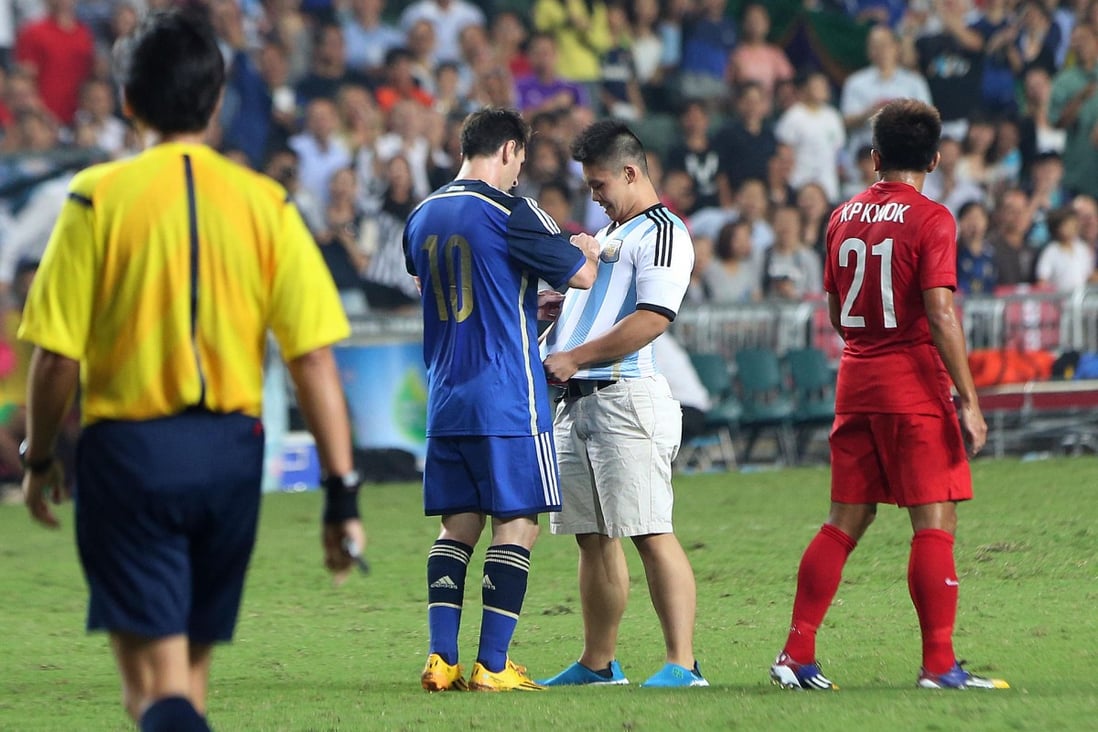 Two-goal Lionel Messi signs the shirt of a delighted pitch invader. Photo: K. Y. Cheng
