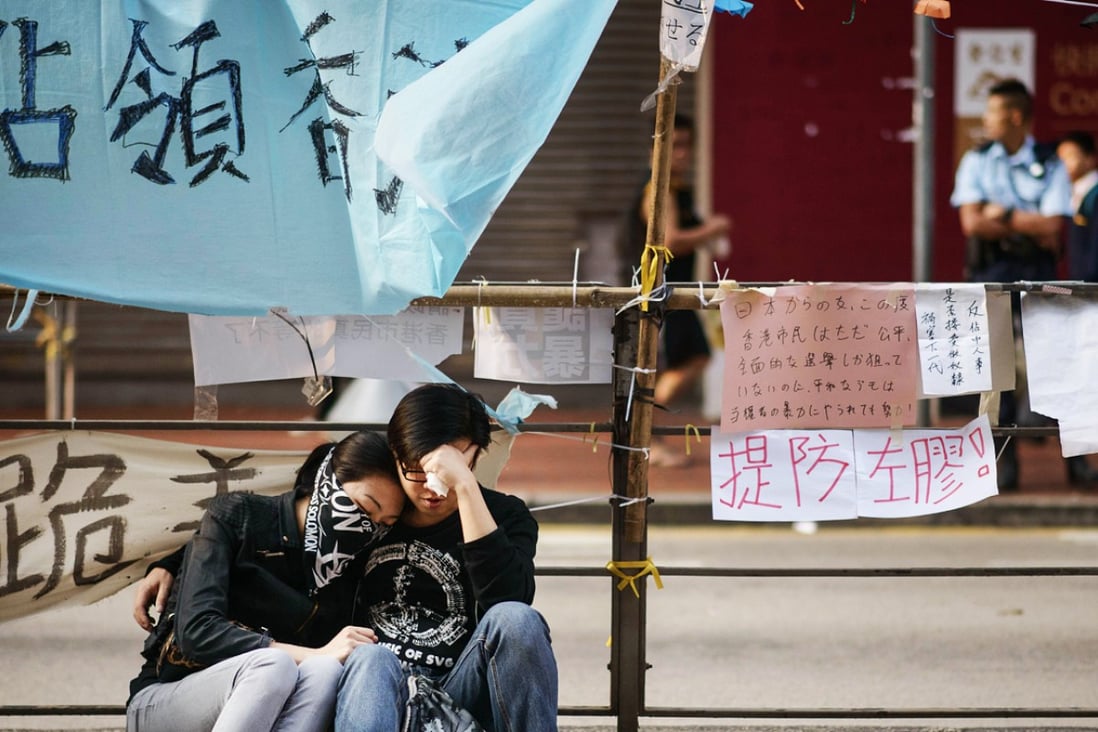 Pro-democracy protesters sit together on a kerb after police removed most of the barricades surrounding the area they were occupying in the Causeway Bay on Tuesday. Photo: AFP