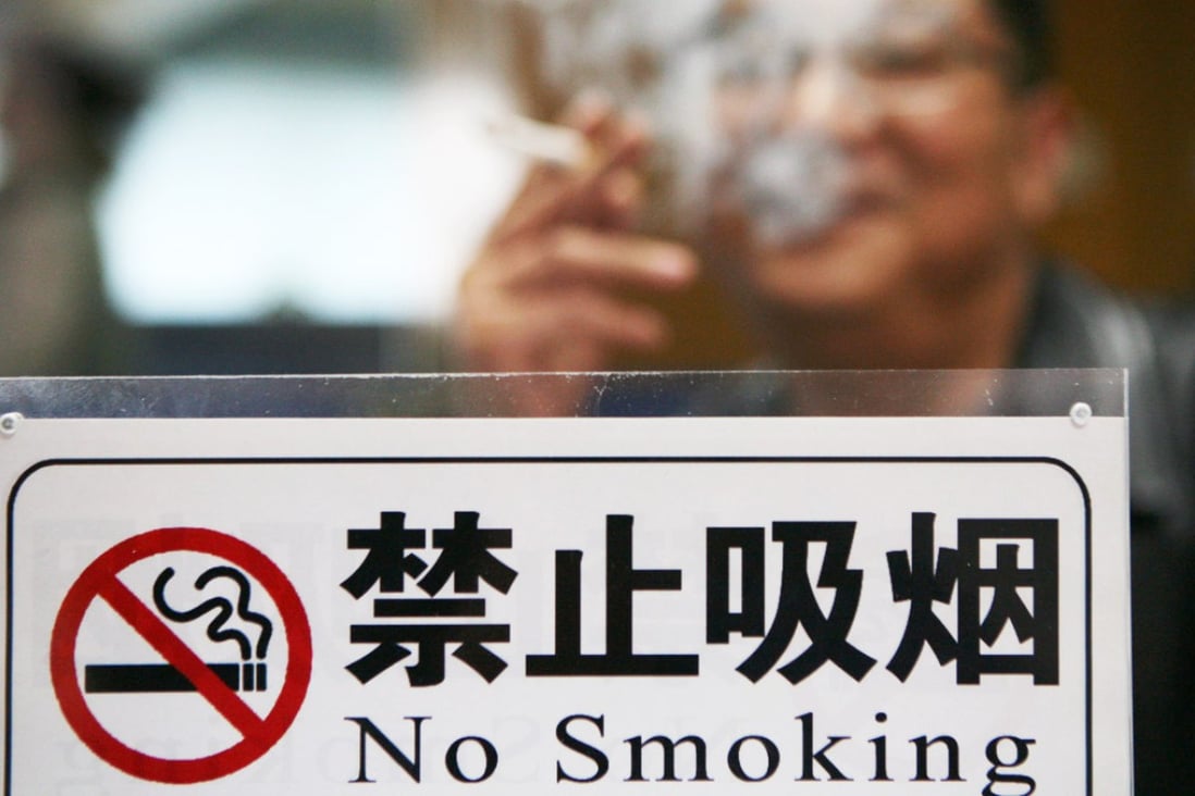 A man lights up in clear sight of a no-smoking sign in Jiangsu province.  Photo: Imaginechina