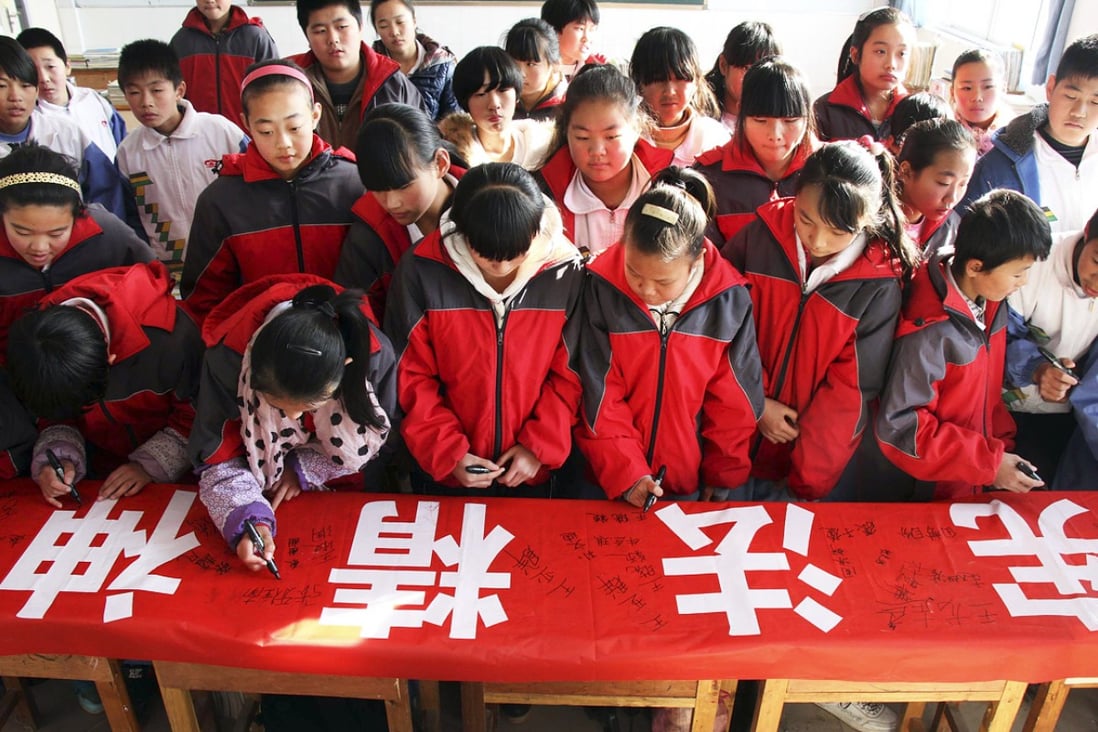 Students sign their names on a banner with the words "Constitution spirit" during an event to mark China's first Constitution Day in a school in Binzhou city. Photo: AP