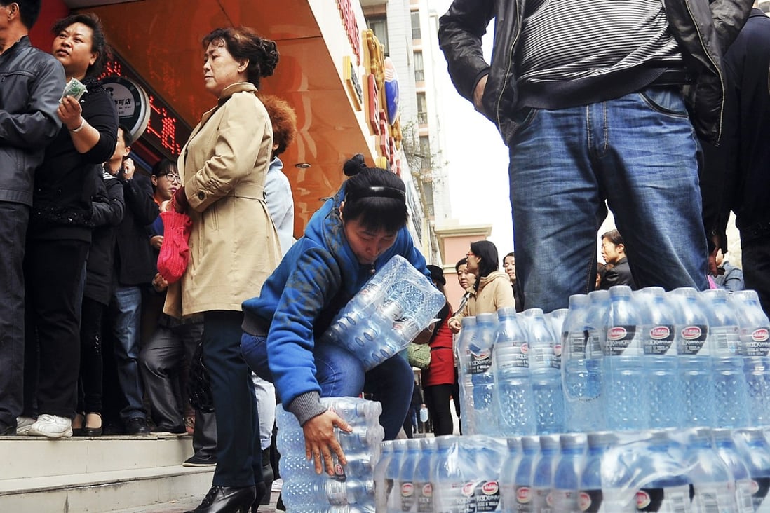 A woman struggles with packs of bottled water she bought in Lanzhou, Gansu province. Many Chinese people rely on bottled water because of high levels of pollution in waterways. Photo: AP