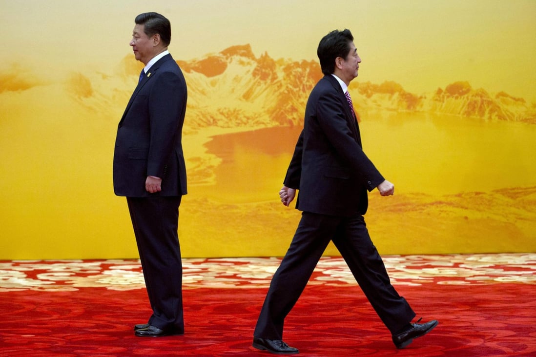 Shinzo Abe (right) walks past President Xi Jinping at the Apec summit in Beijing last month. Photo: AP