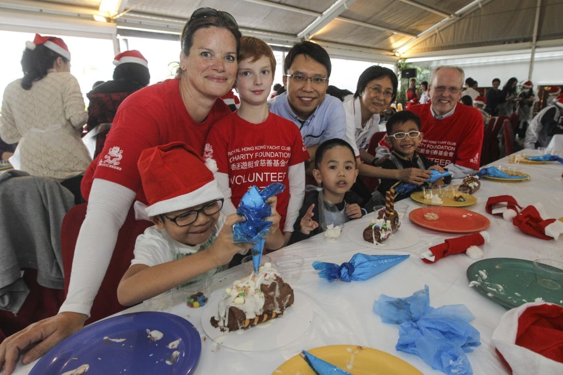 Red Cross Hospital School students decorate Yule logs with (standing from left) Koko Mueller and her son Alex, Dr Ho Chung, principal Sue Chan, and RHKYC general manager Mark Bovaird. 