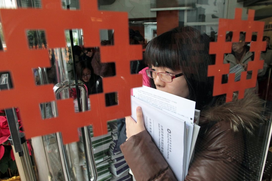 A woman collects an application form and documents for new flats on offer under the Home Ownership Scheme. Photo: Bruce Yan