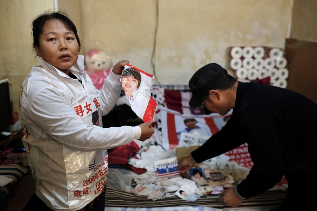 Zhang Xiuhong shows a ripped poster of her missing teenaged daughter, which she says was damaged by the police. Photo: AP