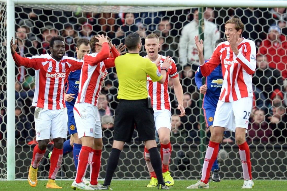 Stoke City players appeal to referee Michael Oliver for handball against United defender Chris Smalling. Photos: AFP 