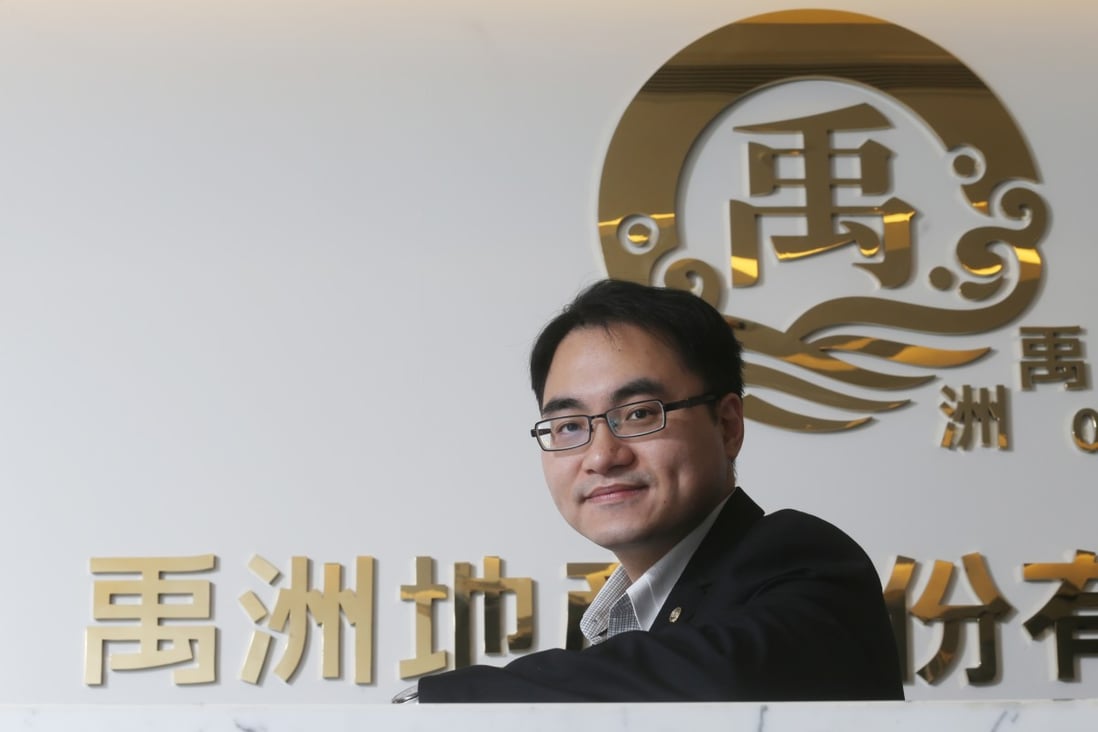 Yuzhou Properties chief financial officer Chiu Yu-kang poses beneath the logo of the company. Photo: David Wong