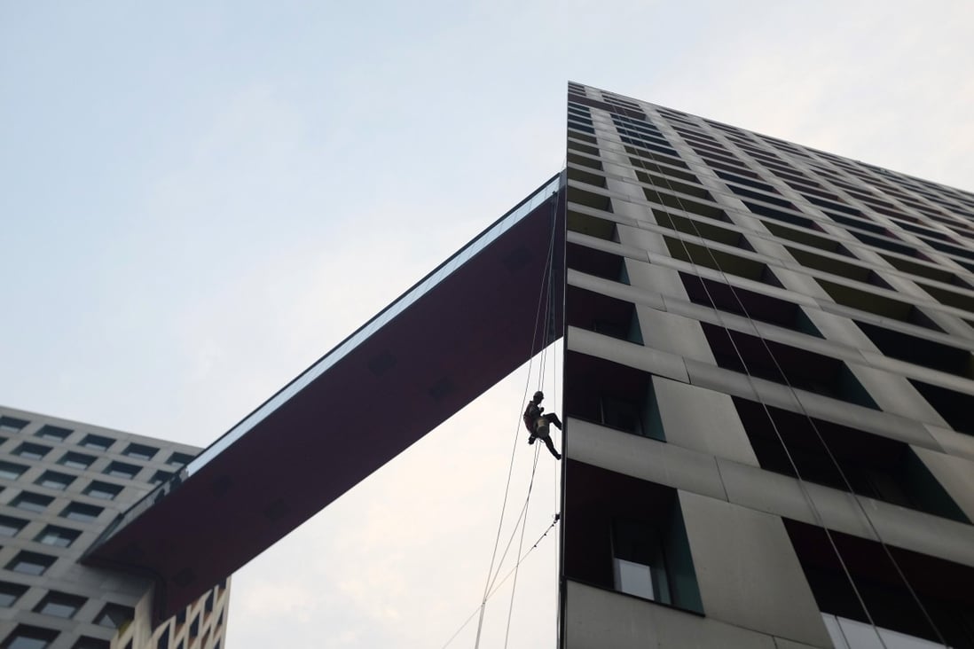 A worker cleans an apartment block in Beijing. The government is taking steps to reduce housing inventory. Photo: Reuters