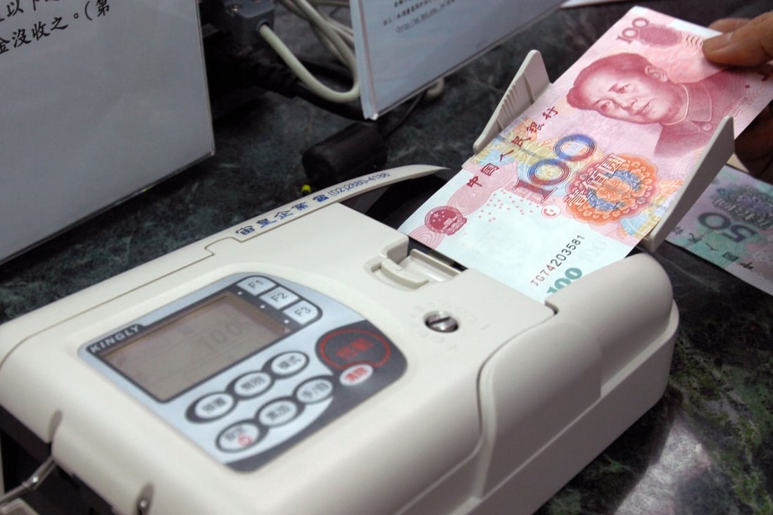 A bank teller checks yuan banknotes. Photo: AFP