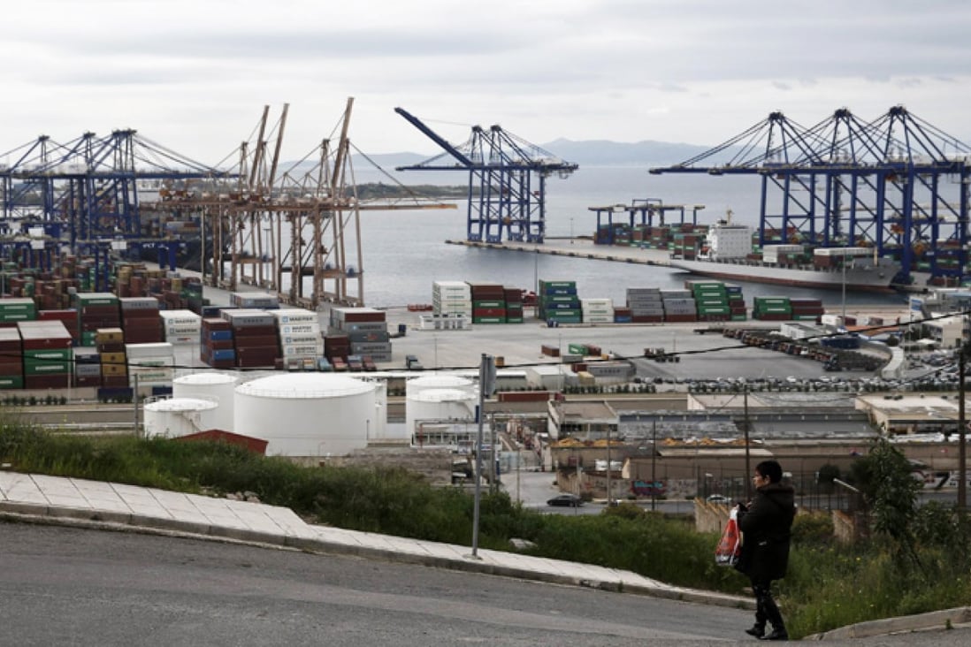 A woman walks by as Piraeus Port is seen in background, near Athens. Photo: Reuters