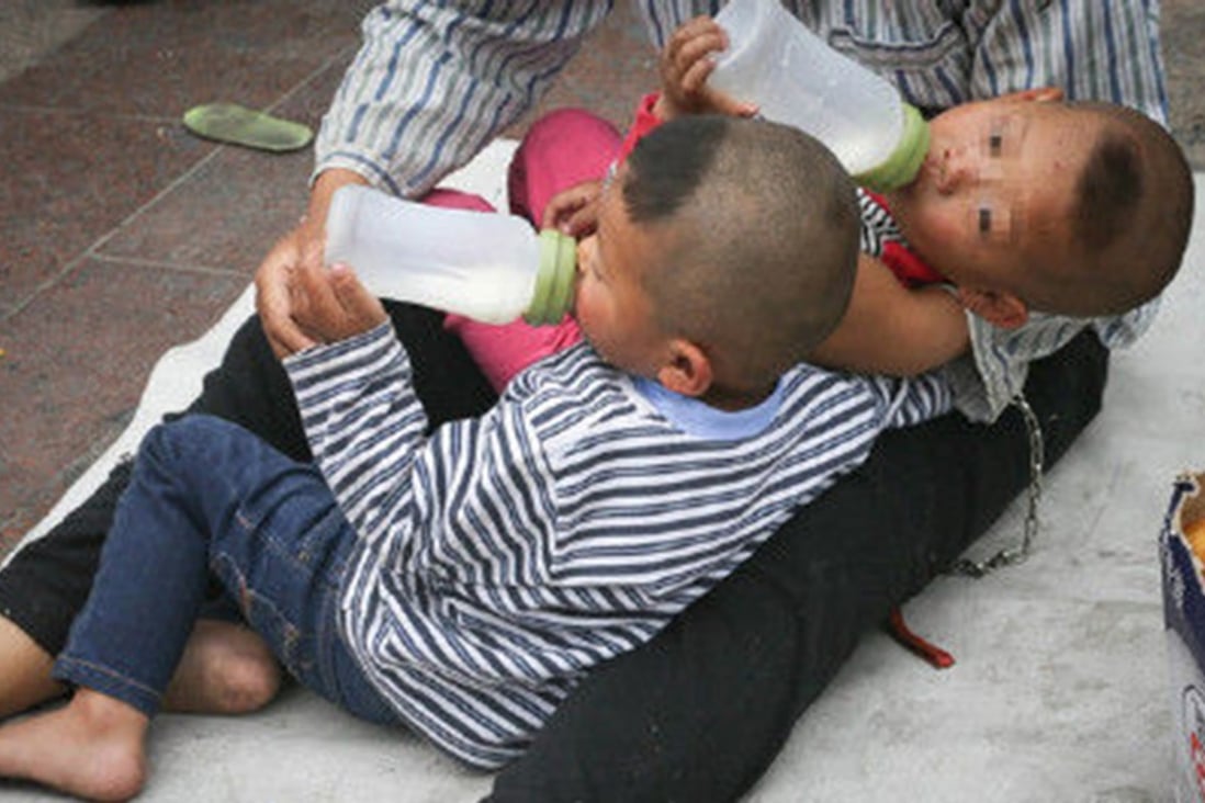 The beggar chained his two children to him outside a Beijing train station. Photo: SCMP Pictures