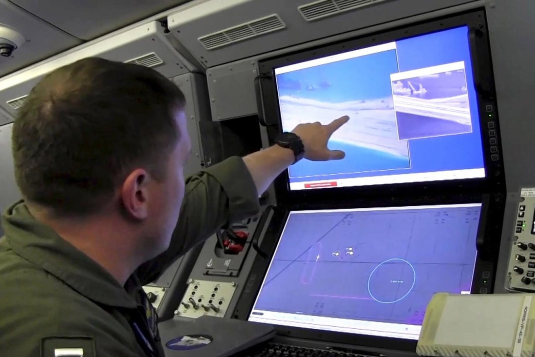 A US Navy crewman (above) aboard a P-8A Poseidon spy plane views a computer screen showing Chinese construction on the reclaimed land of Yongshu, or Fiery Cross Reef, in the disputed Spratly Islands. Photo: Reuters