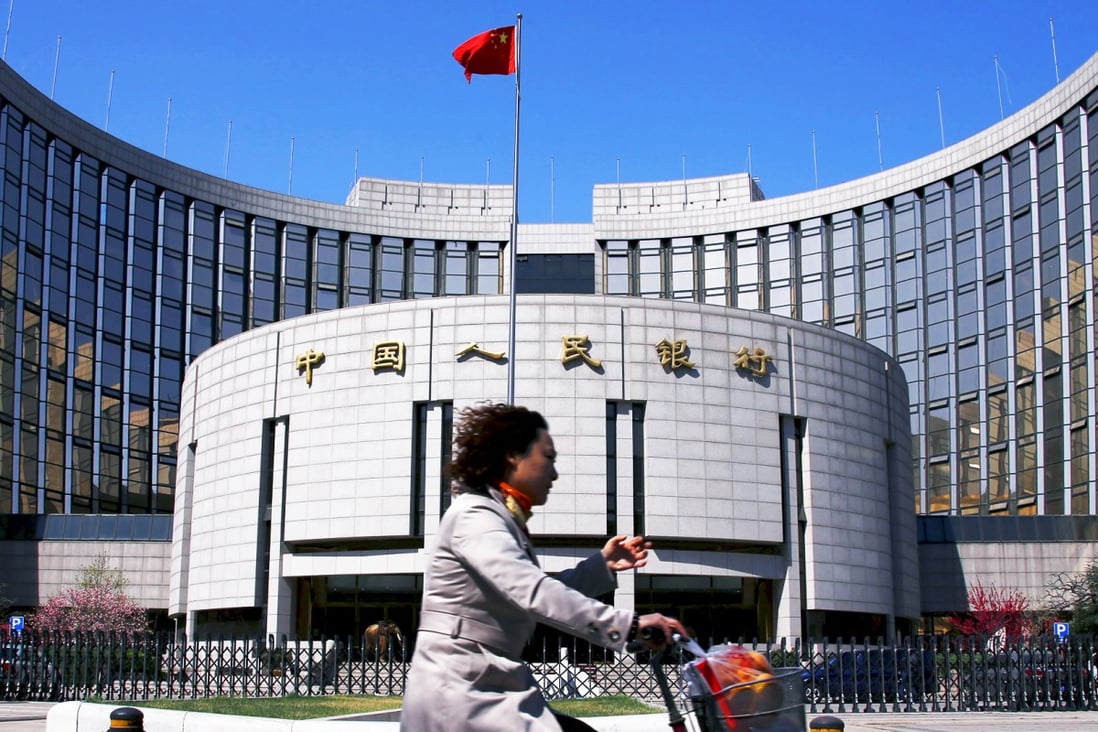A woman rides past the headquarters of the People's Bank of China. The bank wants to find a way to lower the costs of borrowing. Photo: Reuters