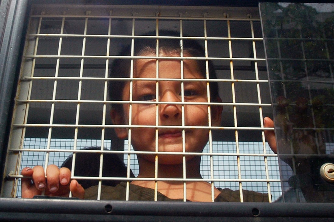 A Uygur boy stands inside a police van in Khlong Hoi Khong in southern Thailand in March, 2014 He was among about 200 Uygurs rescued from a human trafficking camp in Songkhla province. Photo: AP