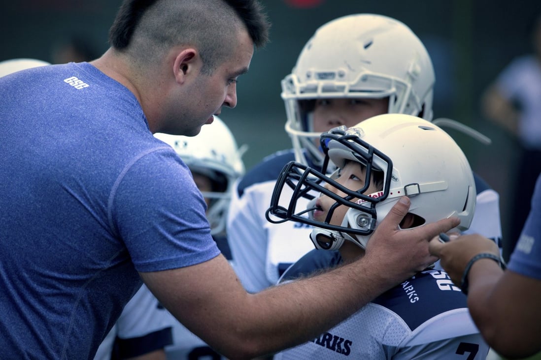 Coach Wes de Kirby gives last-minute instructions to player Liu Jiayou, 9, right, just before the start of their American football game in Beijing earlier this month. Photo: AP