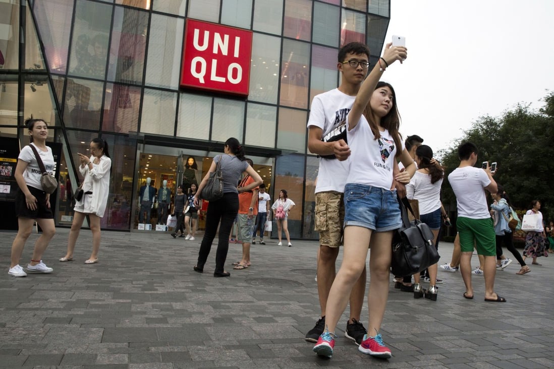 A couple take a selfie outside the Uniqlo flagship store where a steamy video was purportedly taken inside a fitting room in Beijing. The authorities are cracking down on home-made sex videos. Photo: AP