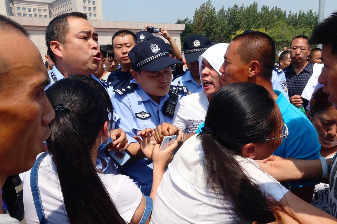 Relatives of missing and dead firefighters, argue with policemen as they gather outside the government hall of Binhai New Area to request more information yesterday. Photo: K. Y. Cheng