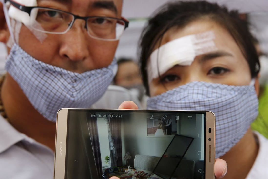 Injured residents evacuated from their home after last week's blasts in Tianjin show a picture on their phone of their damaged property during Wednesday's protest rally. Photo: Reuters