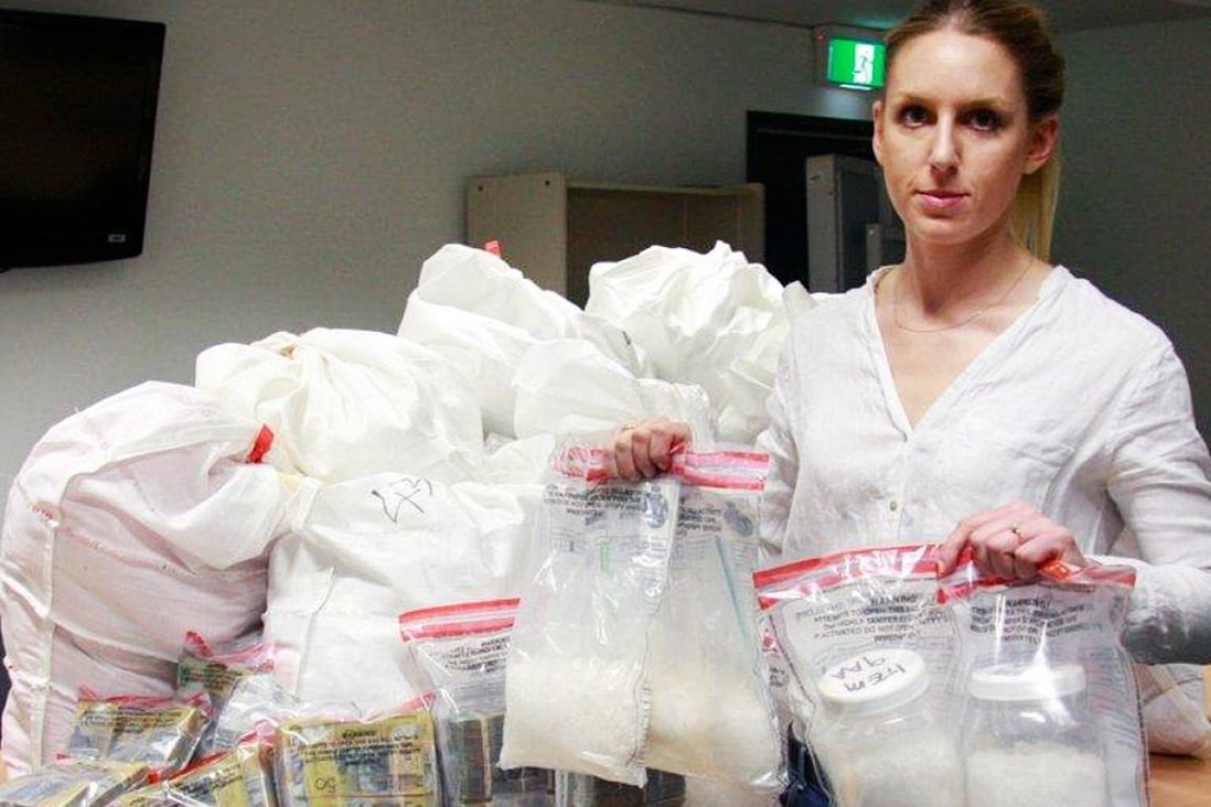 A member of Western Australia police’s organised crime squad poses with the drugs and cash haul. Photo: SCMP Pictures
