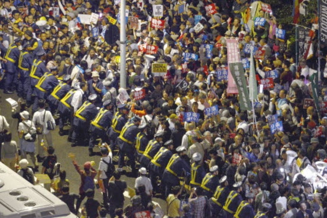 Police officers hold on to fences as a huge crowd gathers in front of the Diet building in Tokyo on the night of Sept. 18, 2015, to oppose the new legislation. Photo: Kyodo