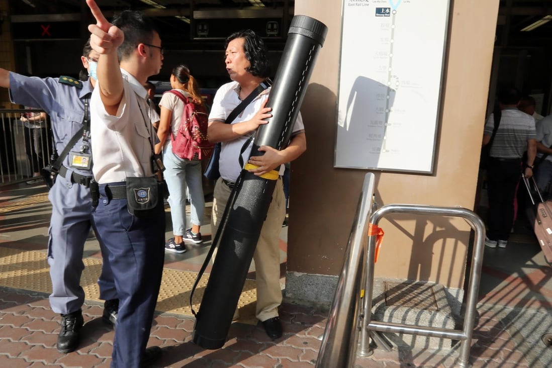 MTR staff move in and prevent a man carrying an oversized item from entering Sheung Shui station yesterday. Photo: Edward Wong