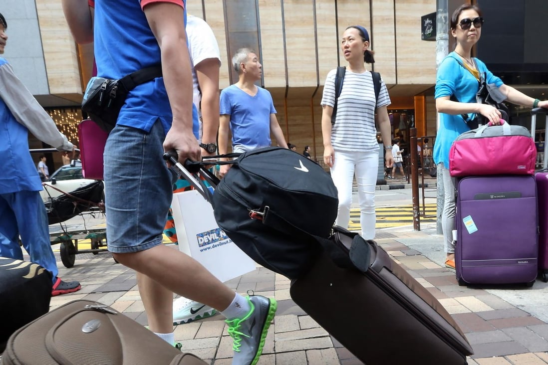 Tourists with their trolleys in the Tsim Sha Tsui shopping area. There are now fewer of them coming to Hong Kong. Photo: Felix Wong