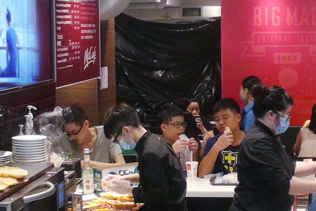 Diners continue with their meals although part of the McDonald's outlet - where the homeless woman died - was cordoned off with a black sheet on Sunday. Photo: SCMP Pictures