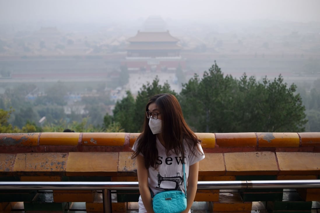A woman wears a mask as she visits a park near the Forbidden City in Beijing on October 7.  Beijing issued a blue warning for air pollution on Friday afternoon, warning the public to reduce outdoor activities and take precautions as the official air quality index reached 344. Photo: AFP
