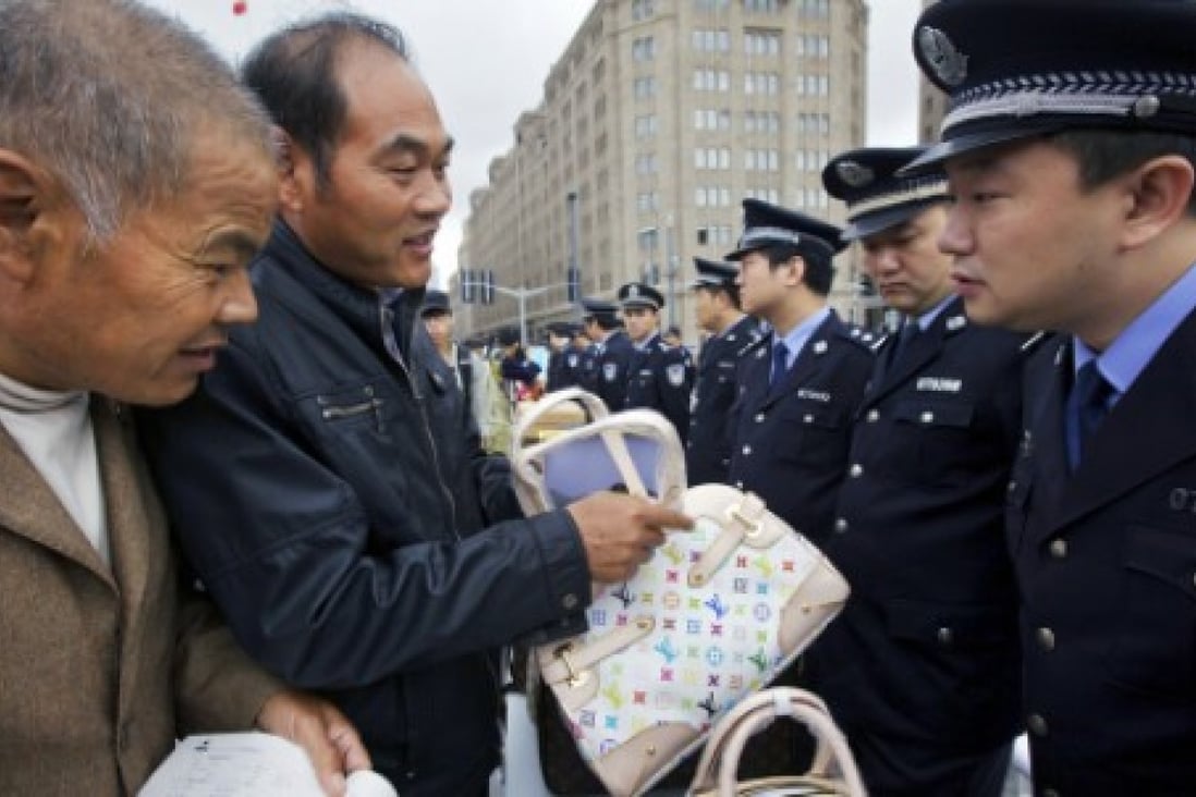 Members of the public examine fake bags during a counterfeit goods awareness campaign run by the police in Shanghai. Photo: AP