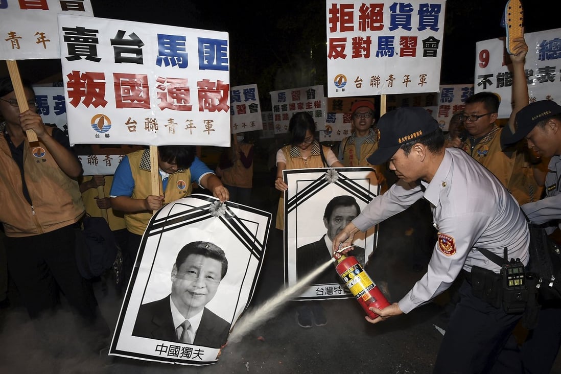 A police officer puts out fire on the portraits of Chinese President Xi Jinping and Taiwan's President Ma Ying-jeou (right) during a protest against the upcoming Singapore meeting between Ma and Xi, outside Taipei Songshan airport on Saturday. Photo: Reuters