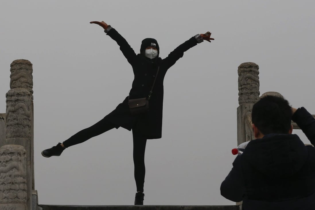 A woman wearing a protective mask against smog poses for photos at the Temple of Heaven Park in Beijing. Photo: EPA